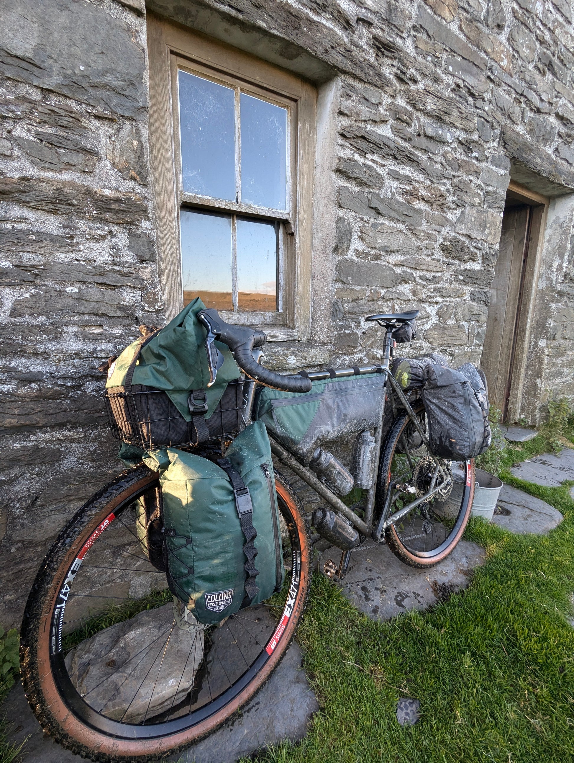Bicycle with gear leaning against a stone building