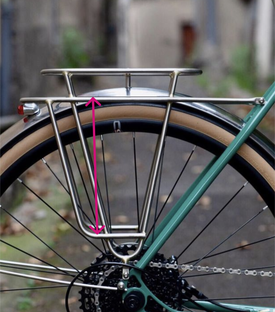 Bicycle rear rack with a pink arrow pointing to it, set against a blurred outdoor background.